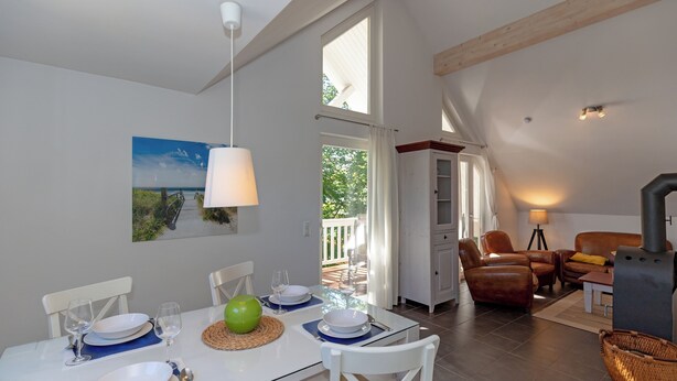 A dining area with a table set for four, a sofa, a fireplace, and a view of the outdoors. - 3-zi-fewo für Max. 4 Pers. im DG, Wlan, Strandnah (Graal-Müritz)