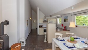 A modern kitchen with white cabinets, a stove, and a dining area with a table set for two. - 3-zi-fewo für Max. 4 Pers. im DG, Wlan, Strandnah (Graal-Müritz)