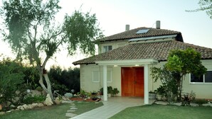 A two-story house with a tiled roof, a front porch, and a well-maintained garden. - Bait Bagiva (Gan Rave)