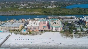 Un hôtel situé sur la côte, composé de plusieurs bâtiments, avec une plage et une étendue d’eau en arrière-plan.