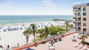 Un hôtel situé en bord de mer, doté d’une piscine, de parasols et d’une jetée.