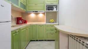 A kitchen with green cabinets, a white refrigerator, a microwave, and a coffee maker. - Apartments IvanBeg (Belgrade)