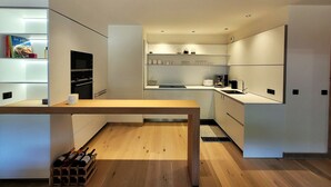 Une cuisine moderne dotée d’appareils électroménagers intégrés, d’une table à manger en bois et d’un meuble à vin.