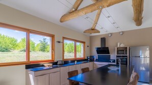 A modern kitchen with large windows, a central island, and a dining area with bar stools.