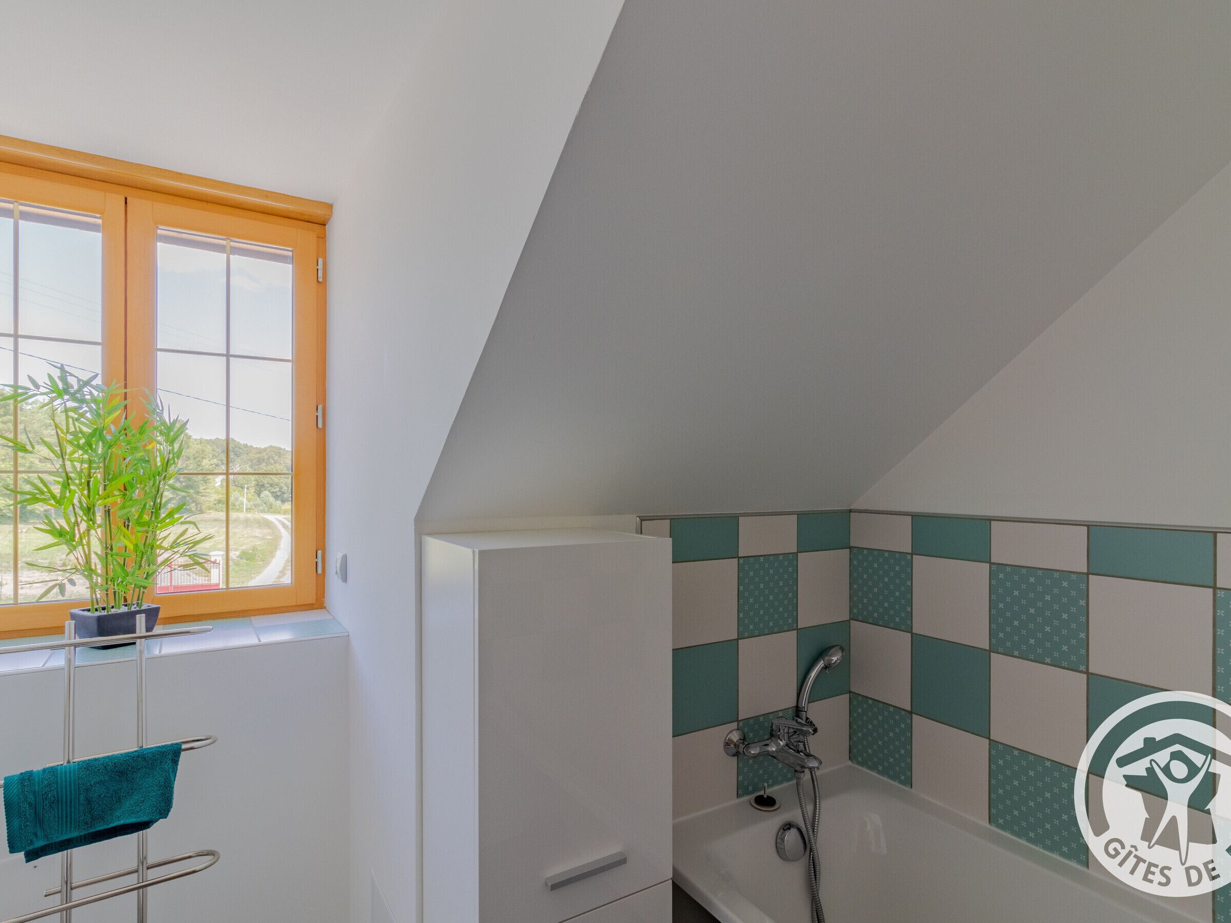 A bathroom with a bathtub, a window with a view, and a towel rack.