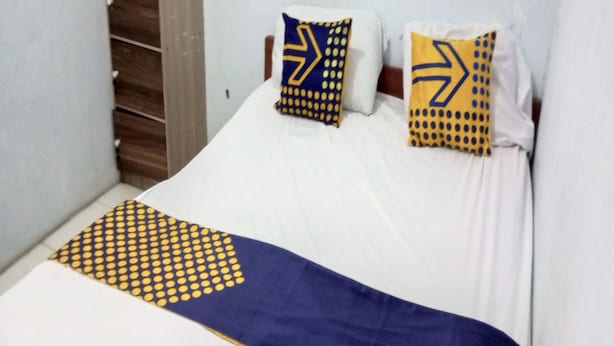Una cama con ropa de cama blanca y dos almohadas con diseños azules y amarillos.