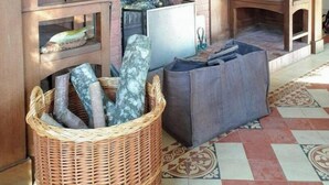 Ein rustikaler Innenraum mit Kamin aus Backstein, Holzböden und einem Korbkaminholz.