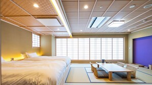 A traditional Japanese-style room with tatami flooring, a low table with cushions, and a large window with grid patterns. - RYOKAN GINKAKU KYOTO (Kyoto)