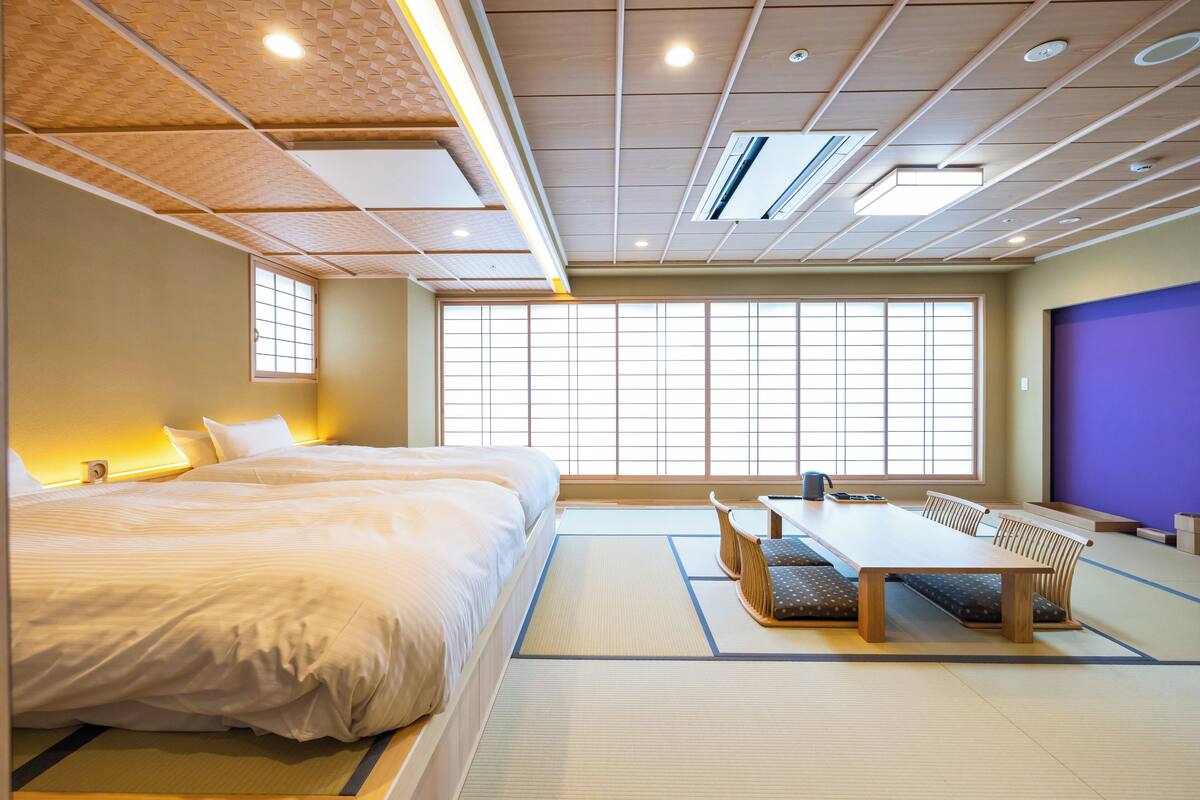 Une pièce de style japonais traditionnel, avec un sol recouvert de tatamis, une table basse avec des coussins et une grande fenêtre à carreaux.