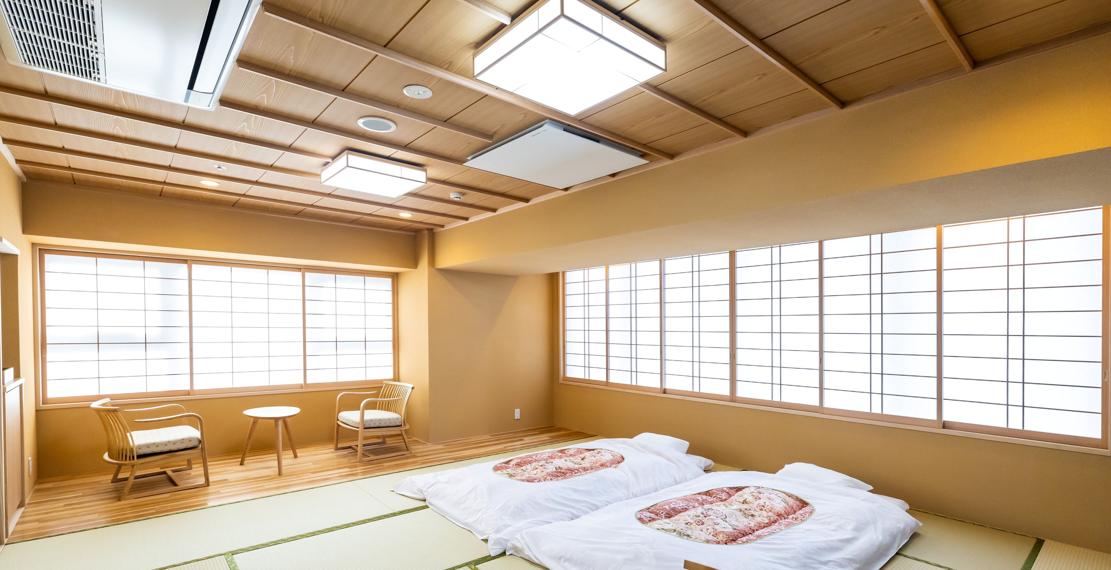 Una habitación japonesa tradicional con suelo de tatami, techo de madera bajo y amplios paneles shoji.
