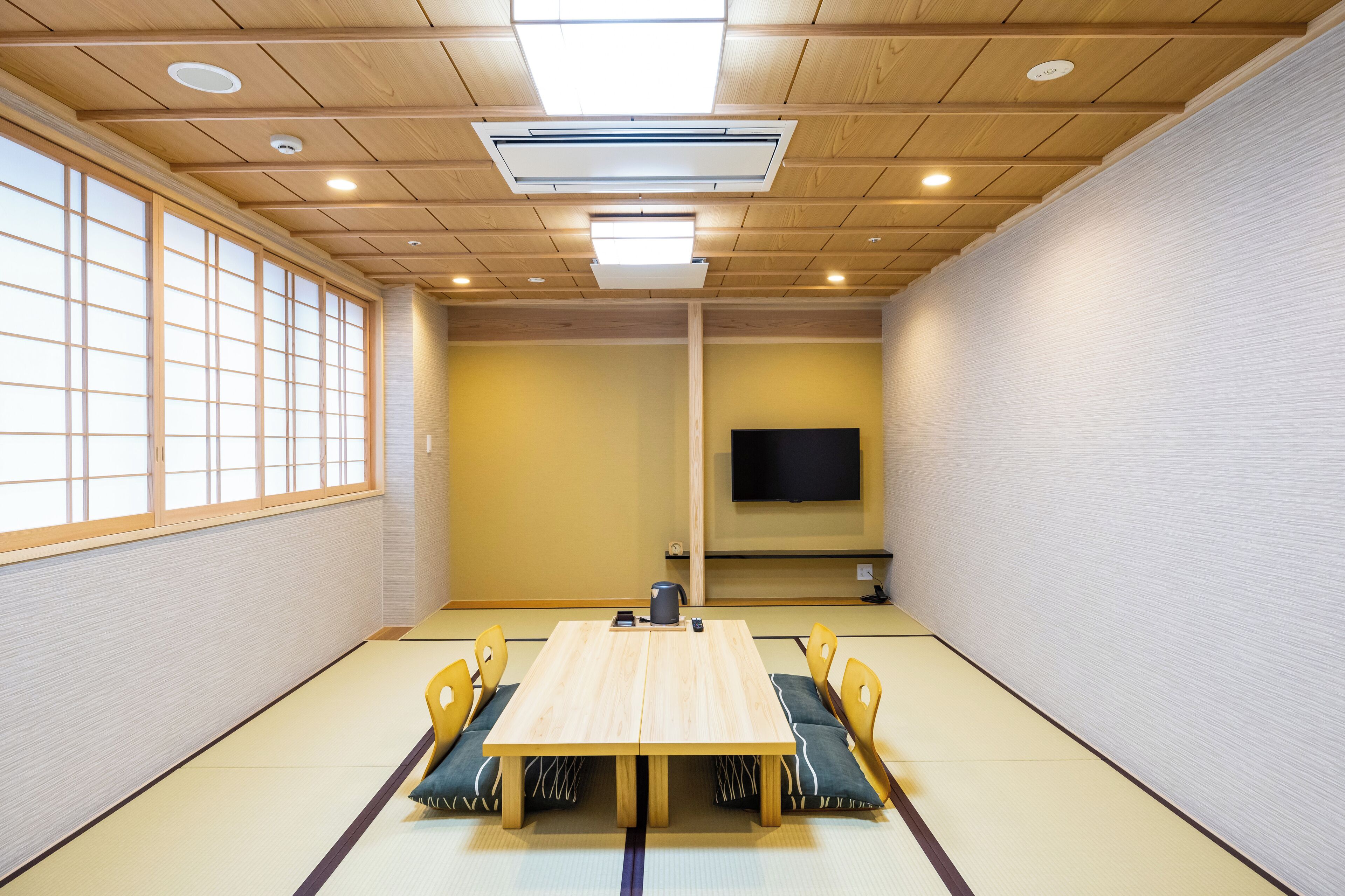 Een traditionele Japanse kamer met tatami vloerbedekking, een lage tafel en houten stoelen.