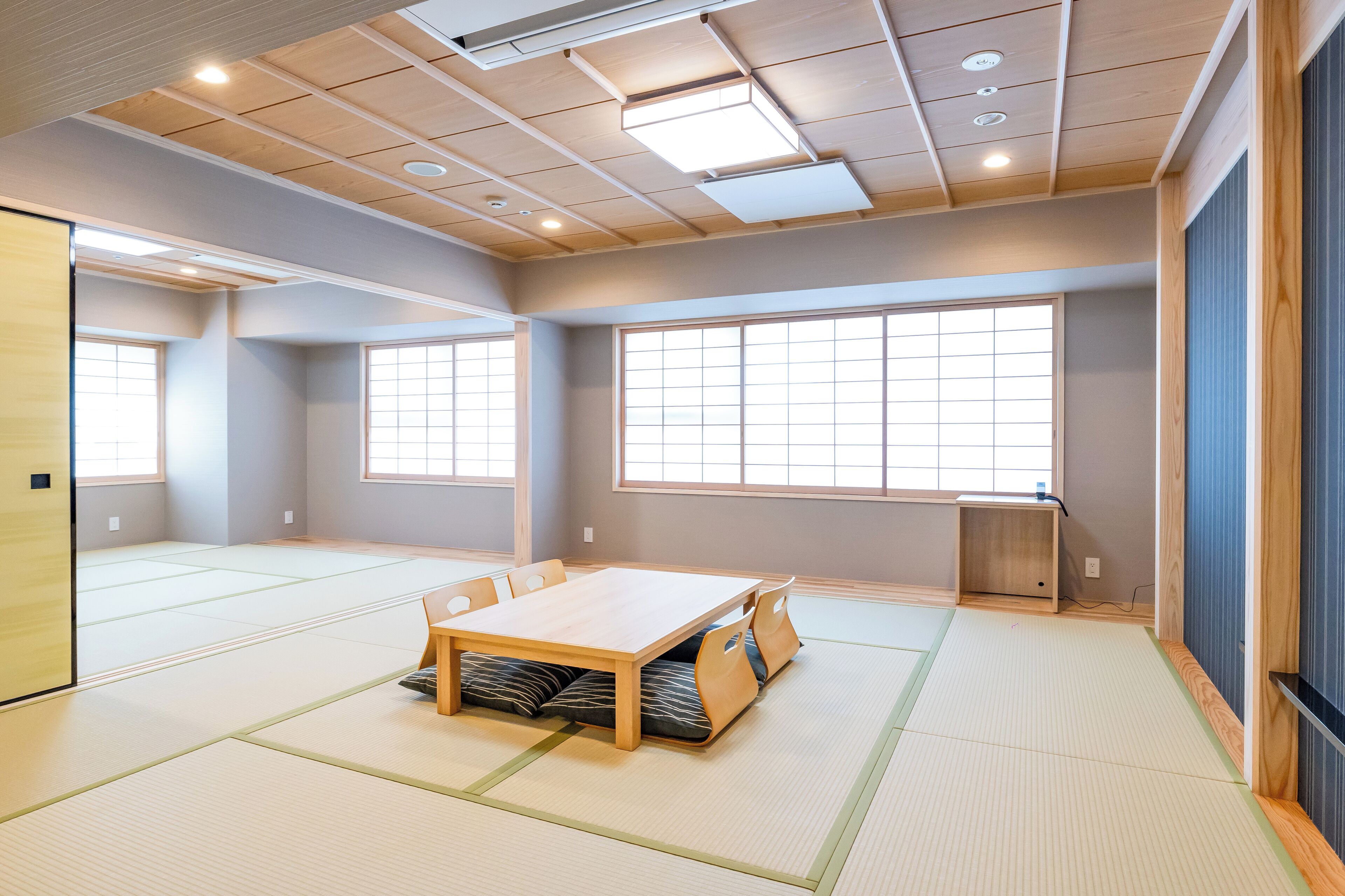 Een kamer met tatami matten, een houten tafel en een groot raam.