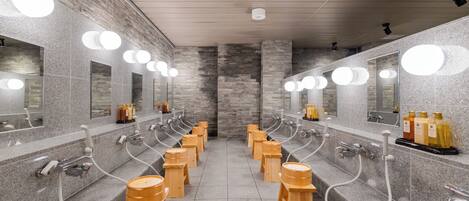 A public restroom with multiple sinks, mirrors, and wooden stools.