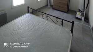 Een slaapkamer met een bed, een dressoir, een radiator en een raam.
