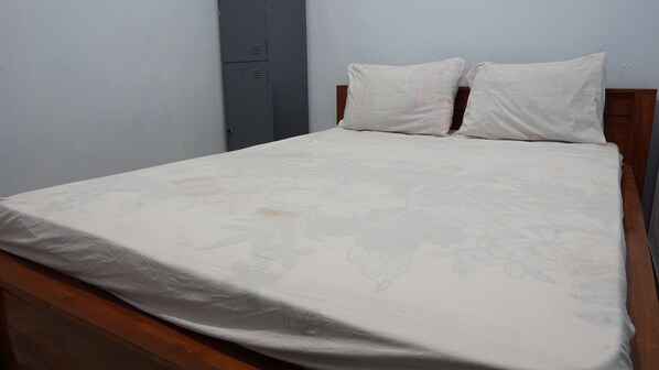 Una cama individual con un edredón estampado con motivos florales, un cabecero de madera y dos almohadas.
