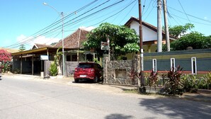 A red car parked in front of a building with a tiled roof and a stone wall.