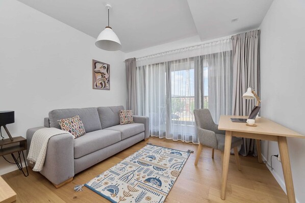 Relax in this stylish living room with a sofa, coffee table, side table, and rug, surrounded by a large window and a beautiful painting.