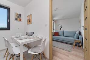 Un espacio moderno para vivir con comedor, sofá y un taburete pequeño.