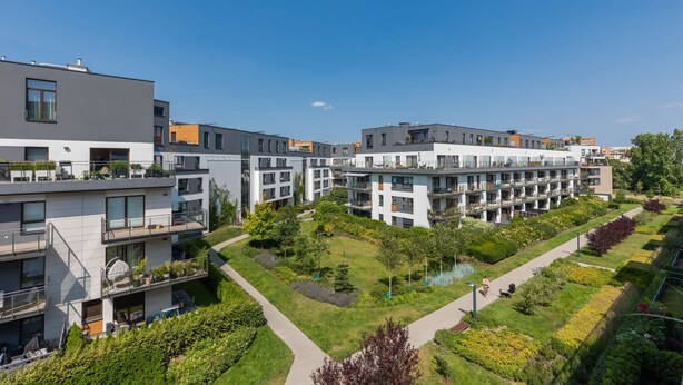 Moderni asuinkompleksi, jossa on useita kerrostaloja, viheralueita ja avoin taivas.
