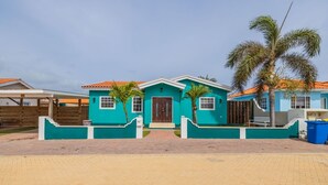 A two-story house with a teal exterior, a brown door, and a red-tiled roof. - Cozy home with private pool! Close to everything! Great dining options! Palm Beach and Hadicurari Beach! (Noord)