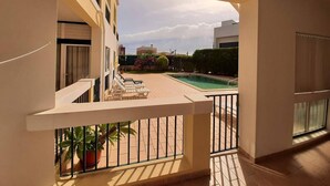 A balcony with a pool view, a white railing, and a potted plant. - Apartment in Condominium with Swimming Pool (Alvor)