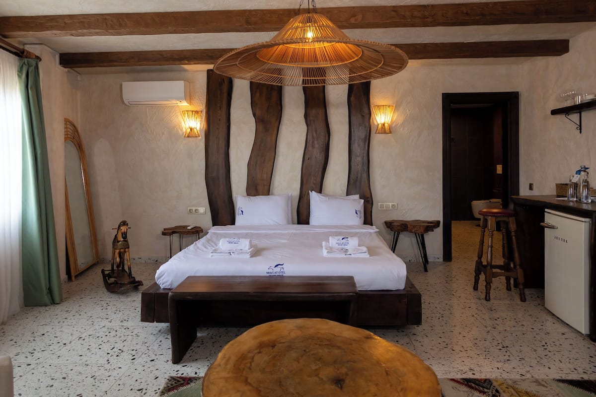 A bedroom with a large bed, a wooden coffee table, a desk, and a bar area.