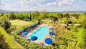 A swimming pool with sun loungers and umbrellas, surrounded by greenery and a view of distant hills. - A magnificent Tuscan farmhouse, surrounded by greenery between the sea and the hills (Pomaia)