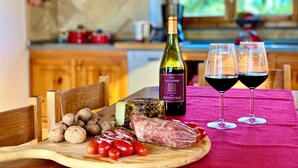 A wooden table with a bottle of wine, two glasses of red wine, a variety of cheeses, cured meats, and nuts. - A magnificent Tuscan farmhouse, surrounded by greenery between the sea and the hills (Pomaia)