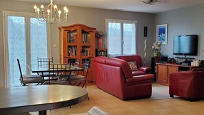 A living room with a dining area, a red sofa, a television, and a bookshelf.