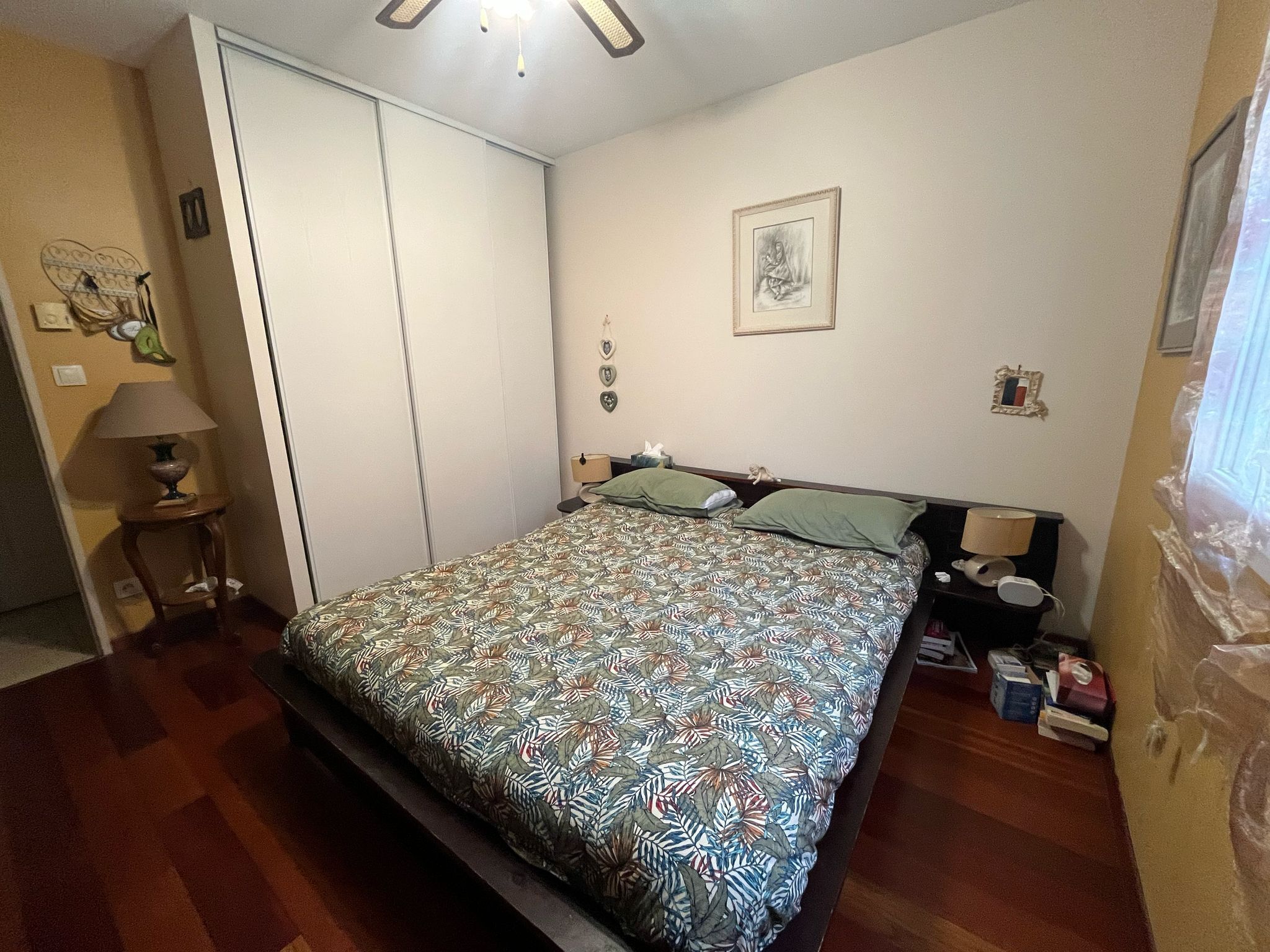 Una camera da letto con un letto, un comodino, una lampada, un armadio e un quadro appeso al muro.