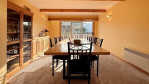 Un comedor con una mesa larga, sillas, un aparador con puertas de cristal y una ventana con vistas.