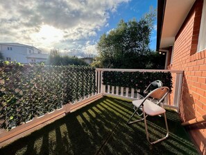 A balcony with a white railing, a small table, and two chairs.