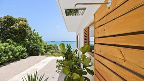 Una casa moderna con fachada de madera, una ventana con contraventanas y vista al mar.