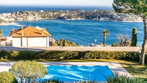 Une piscine avec vue sur la mer et un bâtiment doté d’un toit en tuiles.