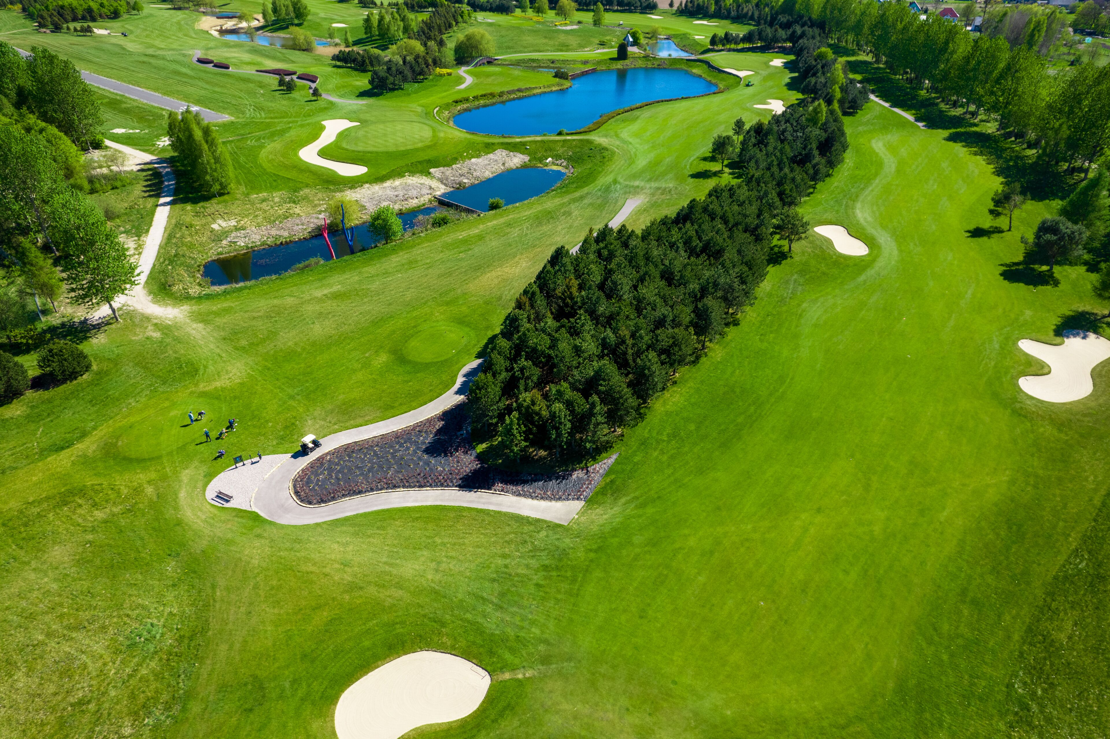 Vista aèria d'un camp de golf amb nombrosos búnquers, obstacles d'aigua i una multitud de persones.