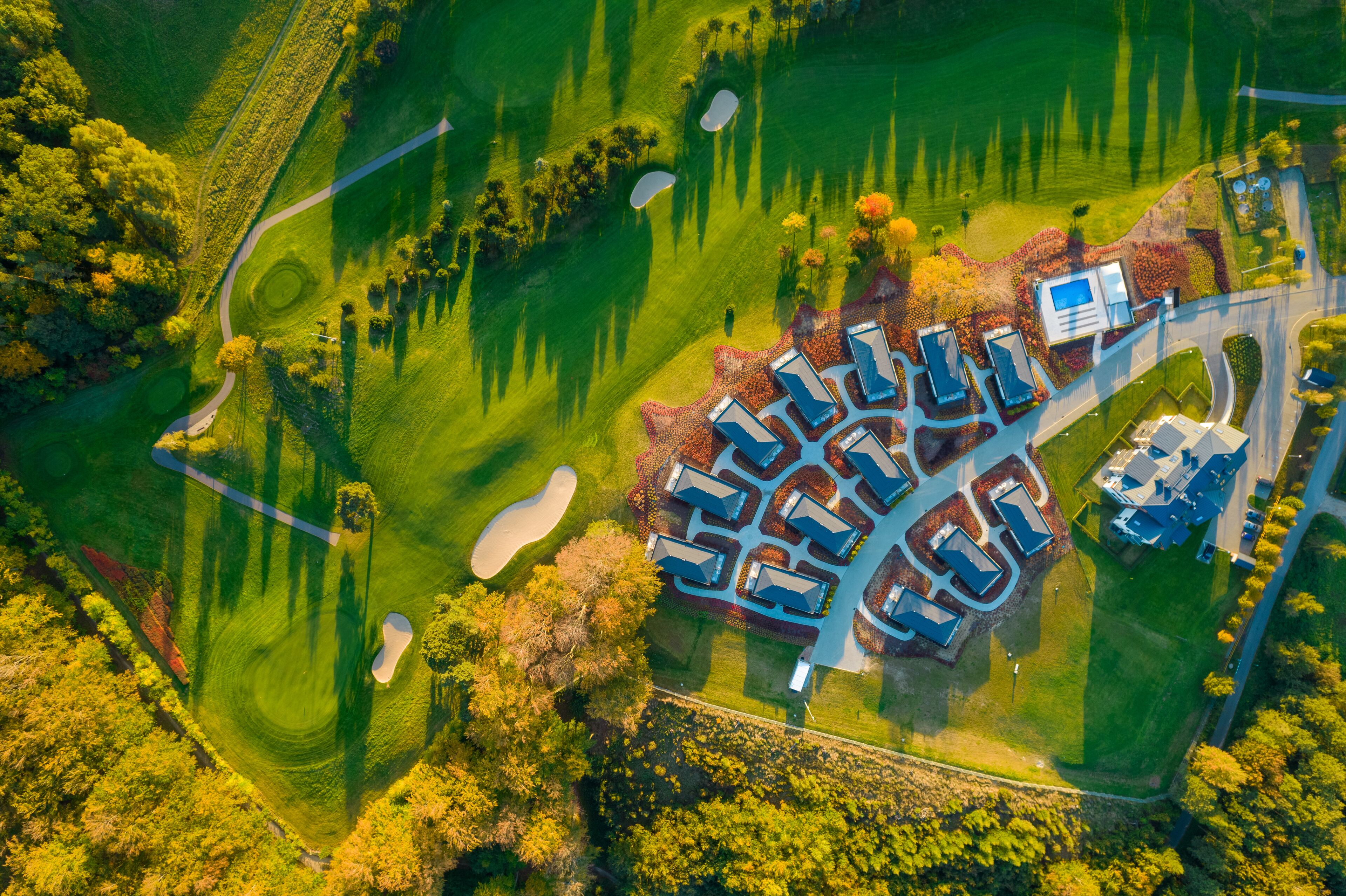 Vue aérienne d’un terrain de golf avec un club-house et un parking.