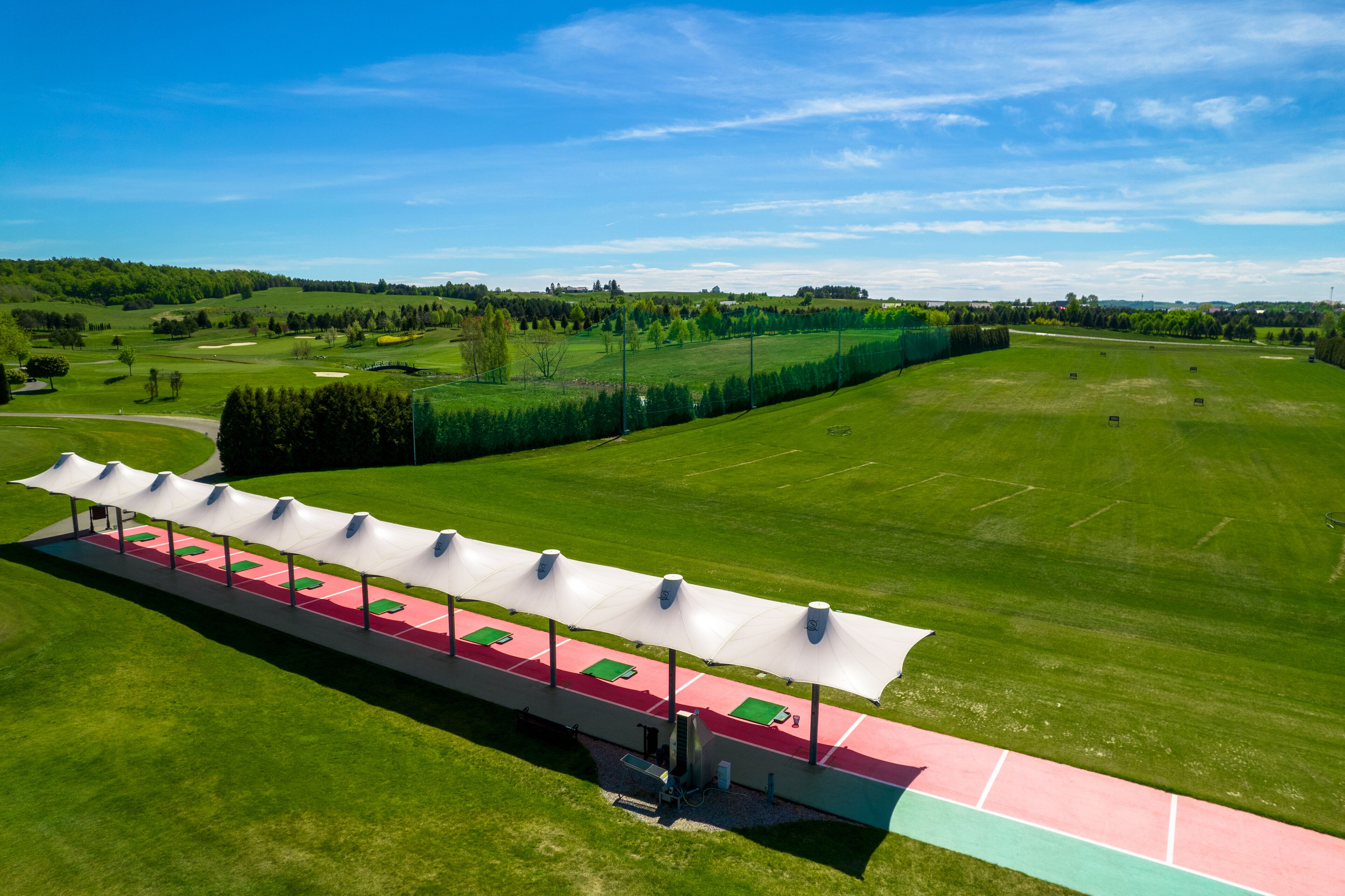 Vista aérea de un campo de golf con una zona de estar cubierta y sillas rojas y verdes.