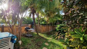 Un patio con mesa y sillas, una parrilla y una valla de madera.