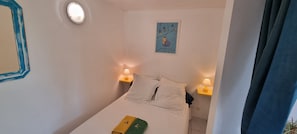 A bedroom with a bed, two bedside lamps, a wall clock, and a framed picture.
