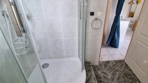 Un baño con ducha de vidrio, un perchero y un inodoro.
