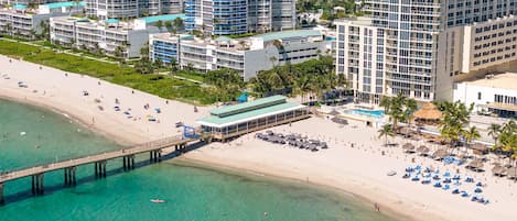 A coastal hotel with a beach view, a pier, and a pool area.