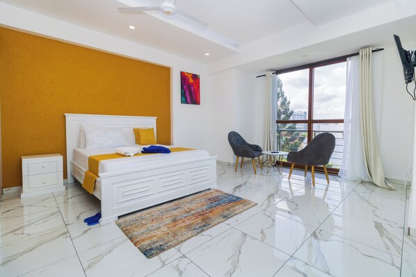 A modern hotel room with a large bed, a small table, and a chair.