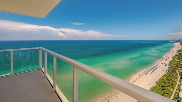 A balcony with a view of a beach and ocean.