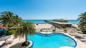A pool area with a view of the beach and ocean, surrounded by palm trees and lounge chairs. - High Floor - Unbelievable Ocean Views - 39th floor 3 Bedroom on the Beach! WOW (Sunny Isles Beach)