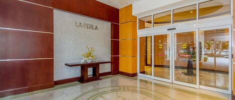 A hotel lobby with a reception desk, a chandelier, and a glass entrance.