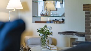 Een woonkamer met een witte bank, een glazen vaas met bloemen, een lamp en een open haard.