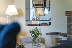 Ein Wohnzimmer mit einer Couch, einer Lampe, einer Vase mit Blumen und einem Kamin.