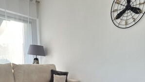 Ett modernt vardagsrum med en beige soffa, ett runt soffbord i marmor och en liten krukväxt.