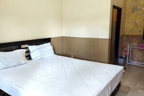 A single bed with white bedding in a room with beige walls and a brown lower section. - Hotel O Kos Moncok (Mataram)