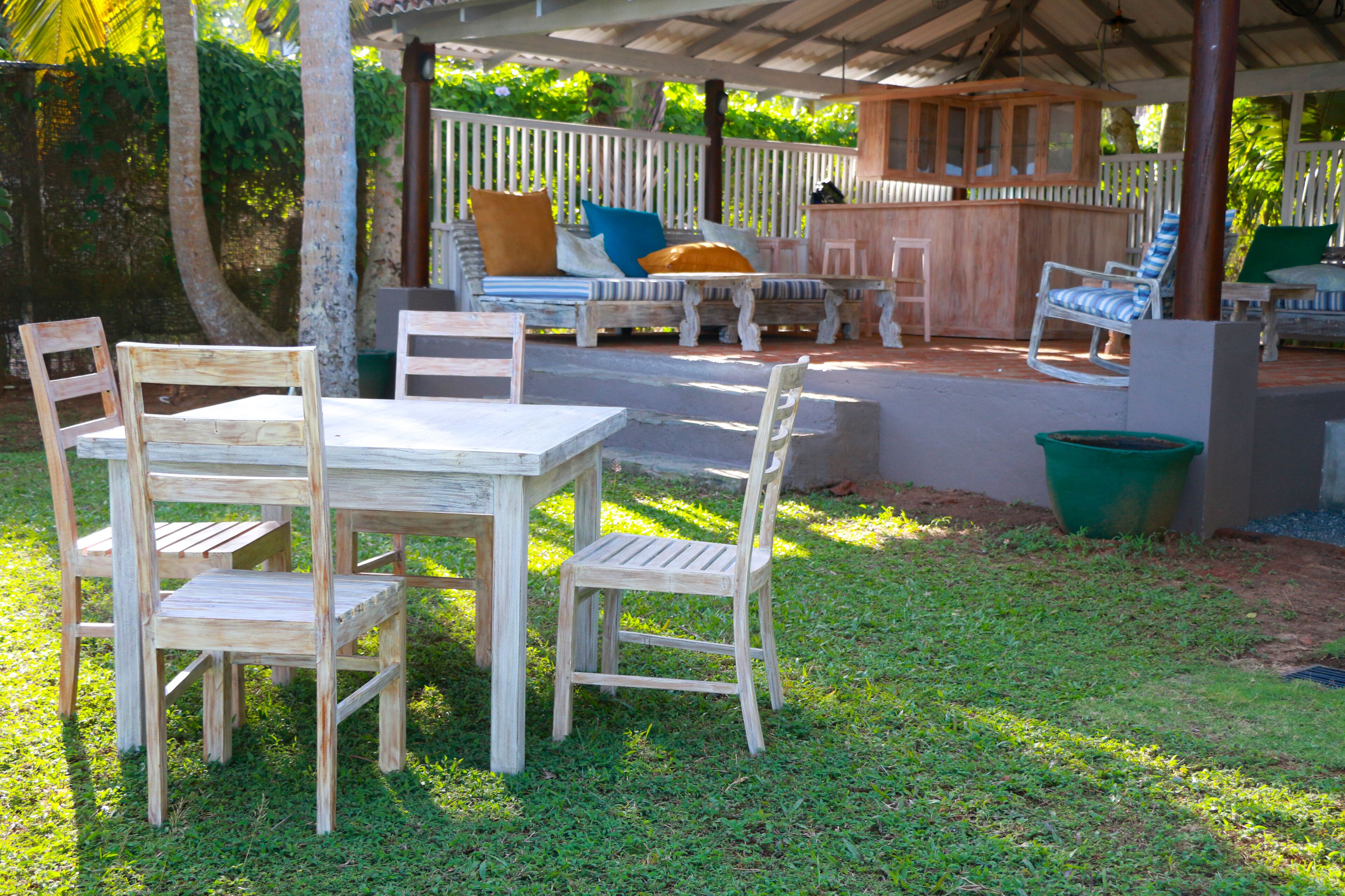 Un área de estar exterior de madera con mesa y sillas, un banco acolchado y una barra de madera.